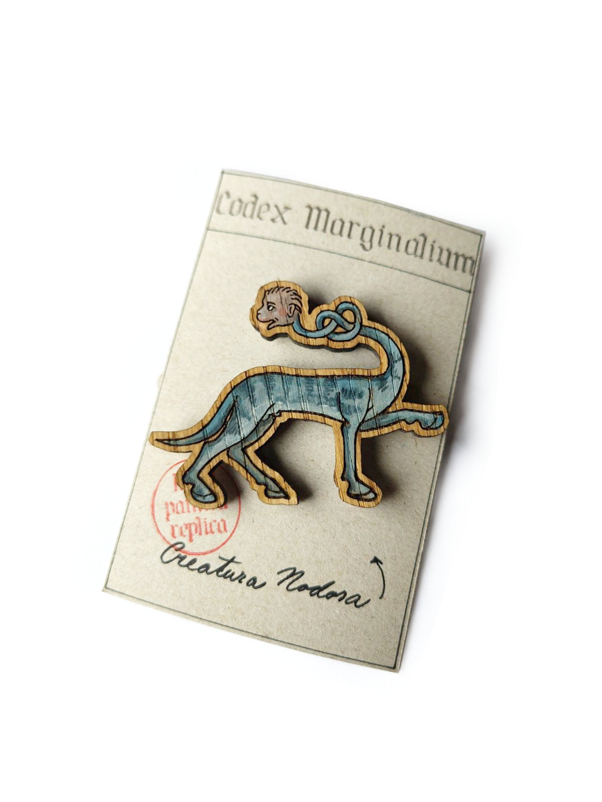 Drevený ručne maľovaný odznak Codex Marginalium s motívom stredovekej drolérie štvornohého stvorenia s krkom zviazaným do uzla