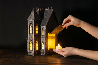 Svietiaci drevený gotický domček vyrezávaný laserom s teplým žltým svetlom v oknách ako halloweenska dekorácia